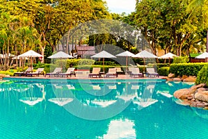 Umbrella and chair around swimming pool in resort hotel for leisure travel and vacation neary sea ocean beach