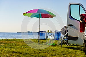 Umbrella with chairs at campervan on beach