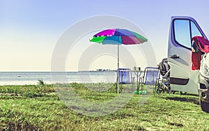 Umbrella with chairs at campervan on beach