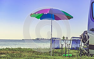 Umbrella with chairs at campervan on beach