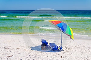 Umbrella and chairs set up at beach shoreline.