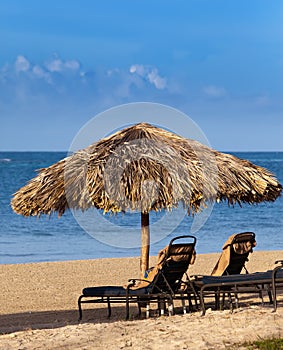 Umbrella and chaise lounges on a beach.