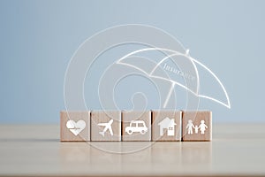 Umbrella cover House, Car, Family, Travel and Health icon on wooden block for assurance life concept