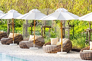 Umbrella and deck chair around outdoor swimming pool in hotel resort
