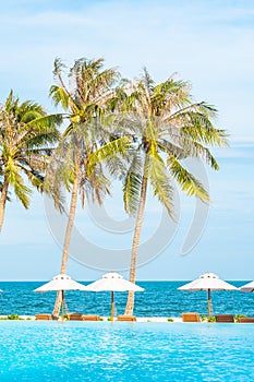 Umbrella and deck chair around outdoor swimming pool in hotel resort