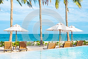 Umbrella and deck chair around outdoor swimming pool in hotel resort