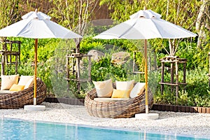 Umbrella and deck chair around outdoor swimming pool in hotel resort