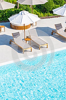 Umbrella and deck chair around outdoor swimming pool in hotel resort
