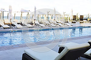 Umbrella and deck chair around outdoor swimming pool in hotel resort nearly sea beach ocean for travel vacation.