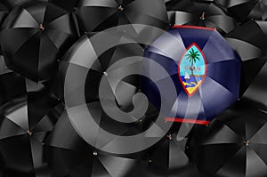 Umbrella with Guamanian flag among black umbrellas, 3D rendering