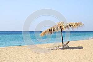 Umbrella and lounge chairs on idyllic beach