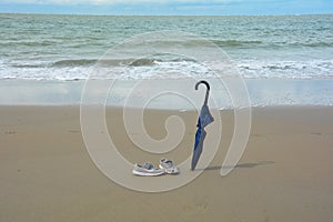 An umbrella and old shoes on the beach