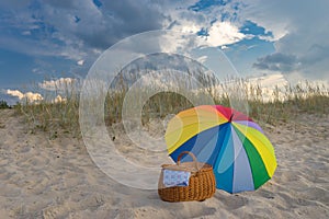 Umbrella and picnic basket against beach and clouds