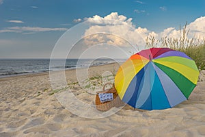 Umbrella and picnic basket against wild beach