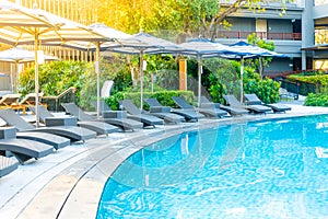 Umbrella and pool bed around outdoor swimming pool in hotel resort for travel holiday vacation