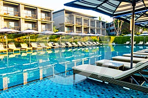 Umbrella and pool bed around outdoor swimming pool in hotel resort for travel holiday vacation