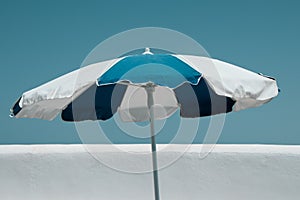 Umbrella in white and blue, protecting from the sun in a blue sky