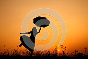 Umbrella woman jumping and sunset silhouette