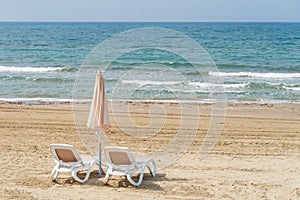 Umbrellas and chaise lounges on the beach. Empty plastic sunbeds near the sea. Tropical vacation, summer background.