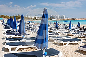 Umbrellas and chaise lounges on the beach. Plastic sunbeds near the sea. Tropical vacation, summer background.