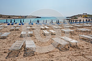 Umbrellas and chaise lounges on the beach. Plastic sunbeds near the sea. Tropical vacation, summer background.