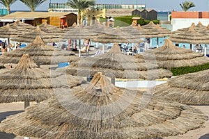 Umbrellas and chaise lounges on the beach. Scenic view of private sandy beach with sun beds from the sea