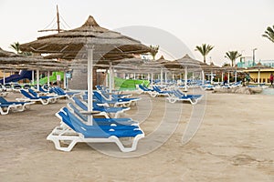 Umbrellas and chaise lounges on the beach. Scenic view of private sandy beach with sun beds from the sea