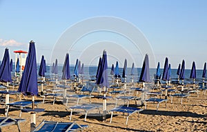 Umbrellas and deckchairs on the beach at sunset on the seashore photo