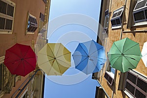Umbrellas of different colors over the street with blue sky as background