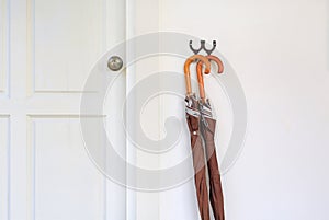 Umbrellas hanging in front of wood door room. Ready to be picked up during rain