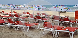 Umbrellas and orange chairs on the beach near the sea
