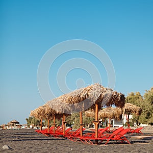 An umbrellas and sun bathing cairs in Perissa