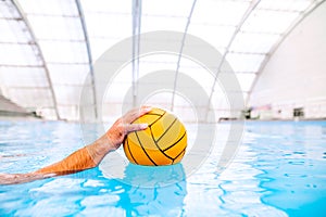Umrecognizable water polo player in a swimming pool.