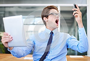 This is unacceptable. A furious young businessman screaming into his cellphone while holding a digital tablet.