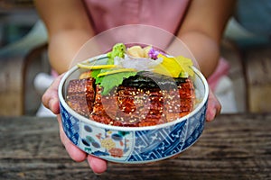 Unagi don bowl in woman hand, Japanese eel grilled with rice Japanese food photo