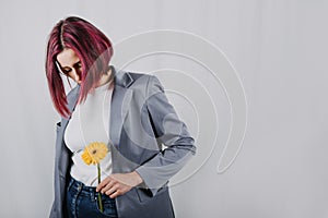 Unaltered candid portrait of young happy young woman with bright red hair with yellow flower