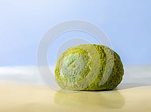 Unappetizing. A greenish moldy tangerine against a blue background.