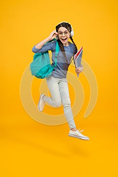 Unassailable childhood. Happy child in midair yellow background. Little girl back to school. School time. Childhood