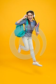 Unassailable childhood. Happy child in midair yellow background. Little girl back to school. School time. Childhood photo
