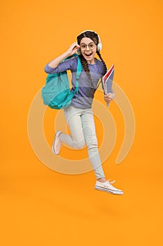 Unassailable childhood. Happy child in midair yellow background. Little girl back to school. School time. Childhood photo