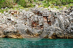 Unassailable rocky seashore with green plants on the top photo