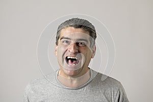 Unattractive 40s or 50s white funny man in sick and mad happy face expression screaming and shouting crazy isolated on grey