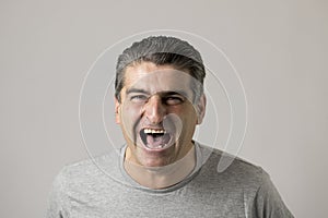 Unattractive 40s or 50s white funny man in sick and mad happy face expression screaming and shouting crazy isolated on grey