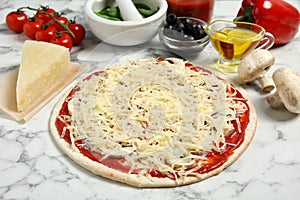 Unbaked pizza and ingredients on table