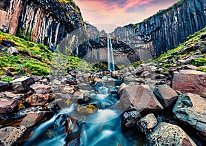 Unbelievable morning view of Svartifoss Black Fall Waterfall. Colorful summer sunrise in Skaftafell, Vatnajokull National Park,