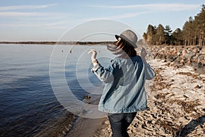 Unbelievably attractive young girl is walking near the seaside with wireless headphones on, dancing to and enjoying the music.