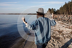 Unbelievably attractive young girl is walking near the seaside with wireless headphones on, dancing to and enjoying the music.