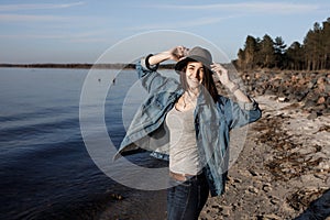 Unbelievably attractive young girl is walking near the seaside with wireless headphones on, dancing to and enjoying the music.