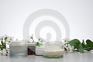 Unbranded Beauty cream and white flowers on light gray background