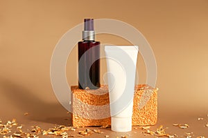 Unbranded dark brown spray bottle, white squeeze bottle cream tube, golden rectangular shape and pieces of gold paper on golden